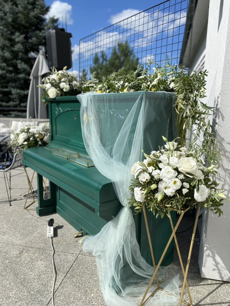 Prawdziwa realizacja pracowni: białe kwiaty i zieleń przy zielonym pianinie
